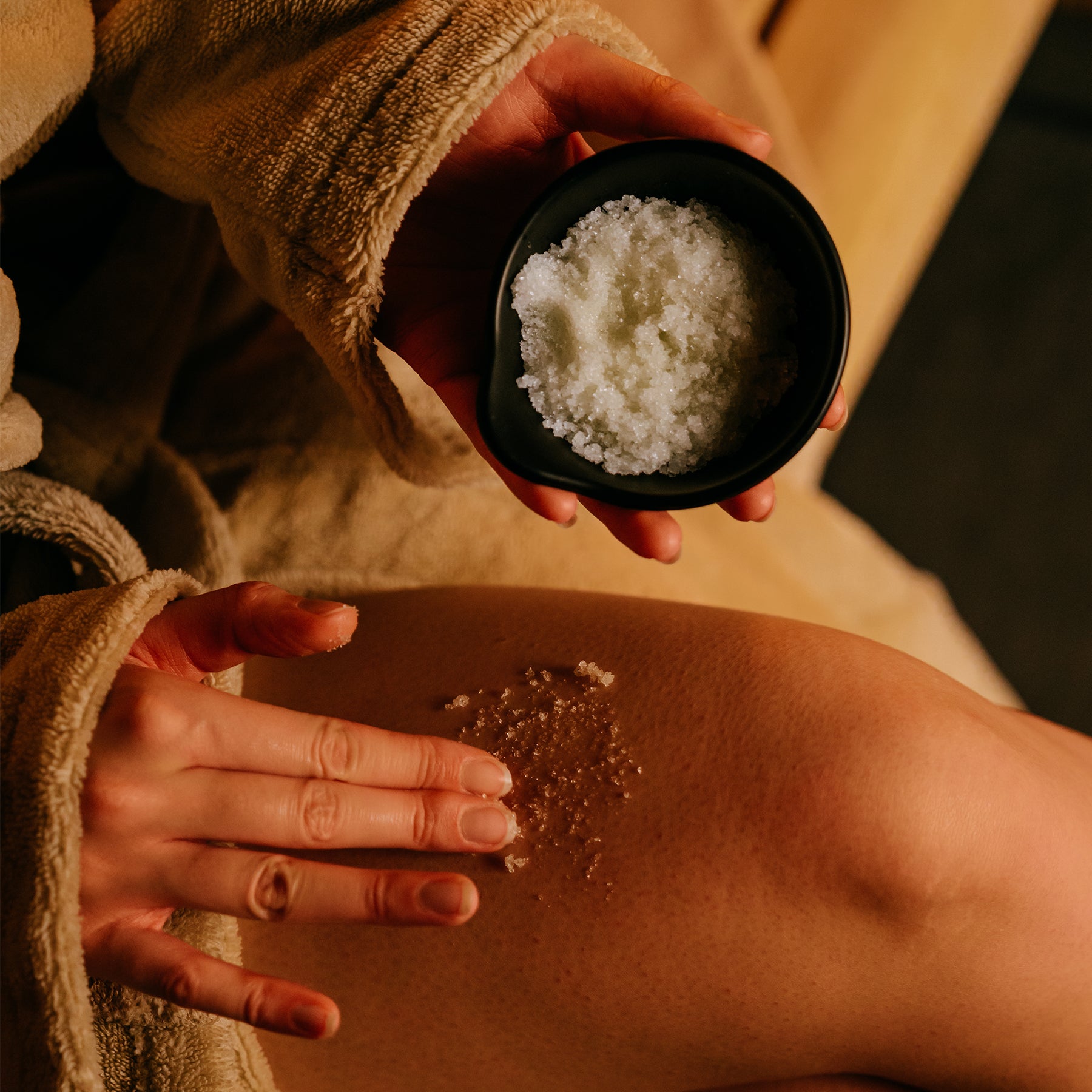 Hand, die das Body Scrub Orange von MyWellness auf die Haut aufträgt