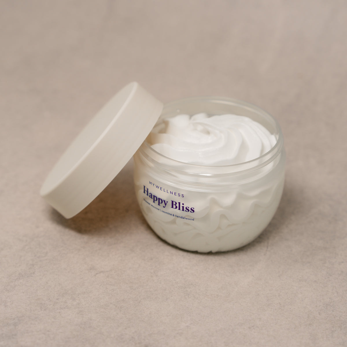 Geöffnete Happy Bliss Shower Mousse von MyWellness mit angelehntem Deckel vor beigem Hintergrund