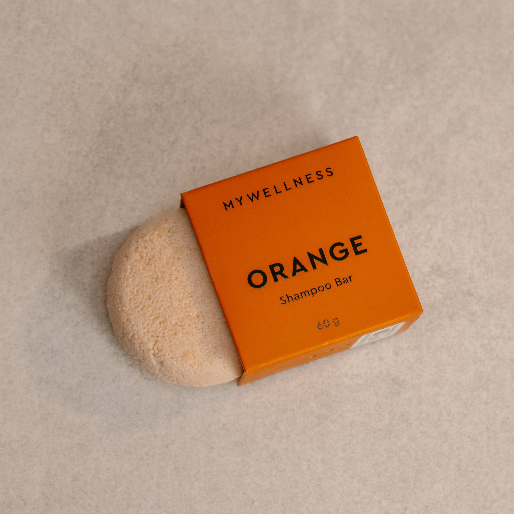 Shampoo Bar Orange liegend neben der nachhaltigen Produktverpackung auf hellem Hintergrund.