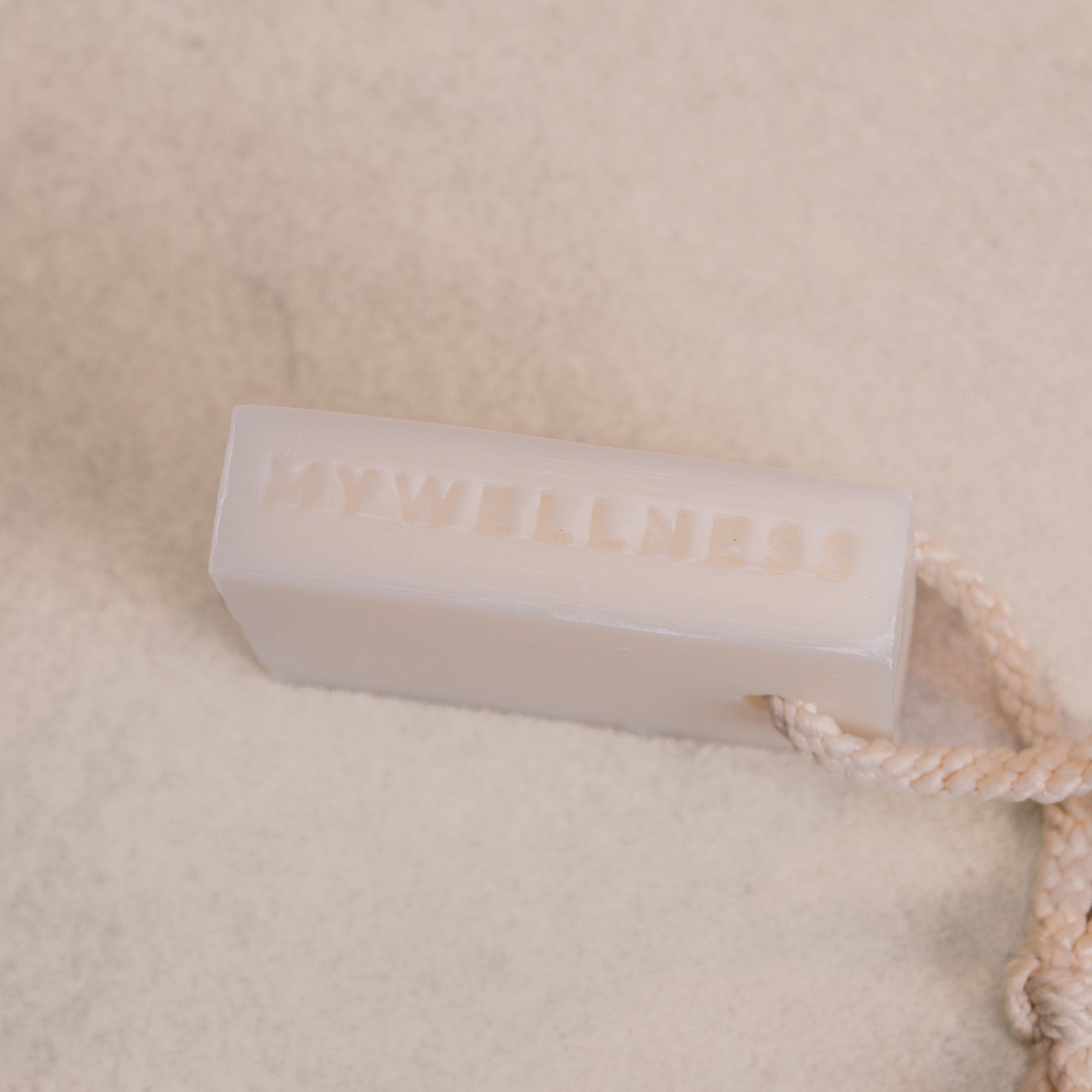 Fester weißer Shower Bar Seifenblock mit eingeprägtem MyWellness Logo und Kordel.