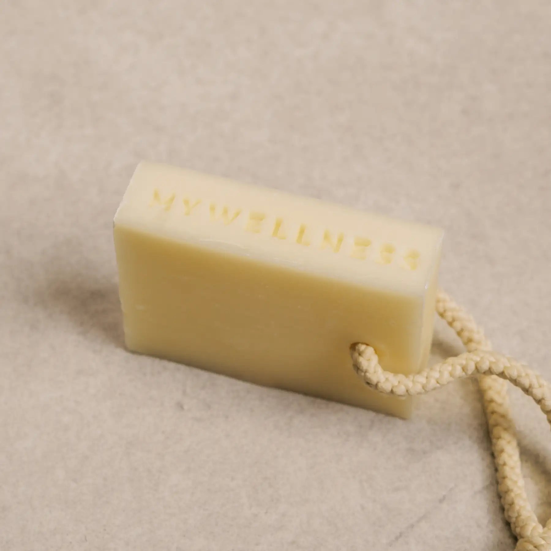 Detailaufnahme der MyWellness Shower Bar Lemon – natürliche Zitronenseife mit strukturierter Oberfläche, Aufhängeschnur und MyWellness Logo-Einprägung