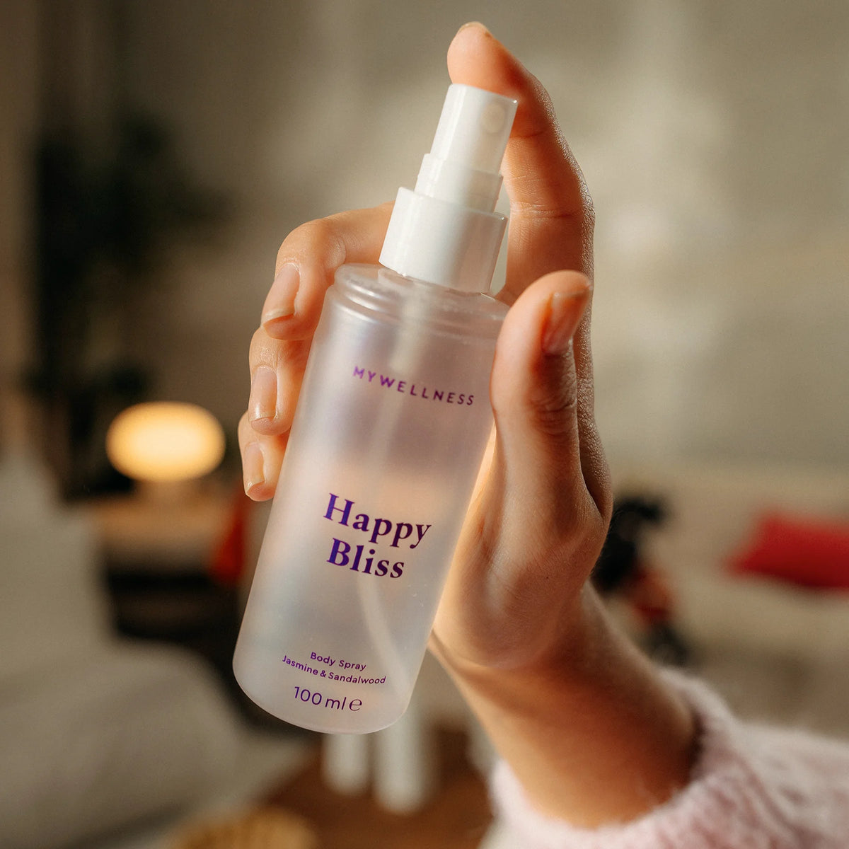 Hand betätigt den Sprühkopf des Happy Bliss Body Spray mit Jasmin und Sandelholz von MyWellness