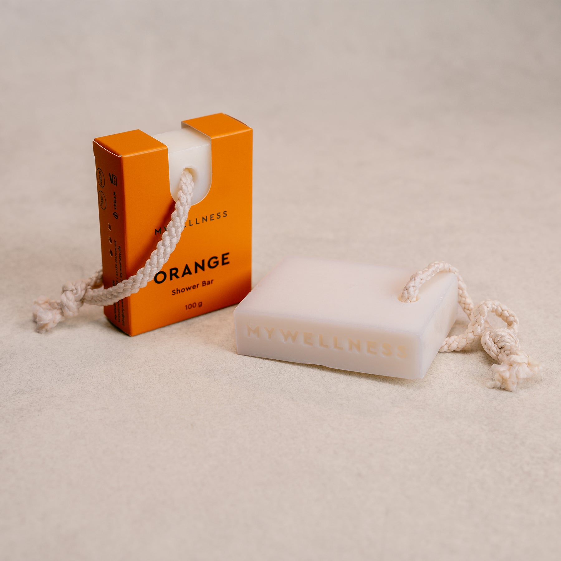 Seitliches Produktfoto der festen Shower Bar Orange mit Verpackung daneben mit Kordel auf hellem Untergrund.