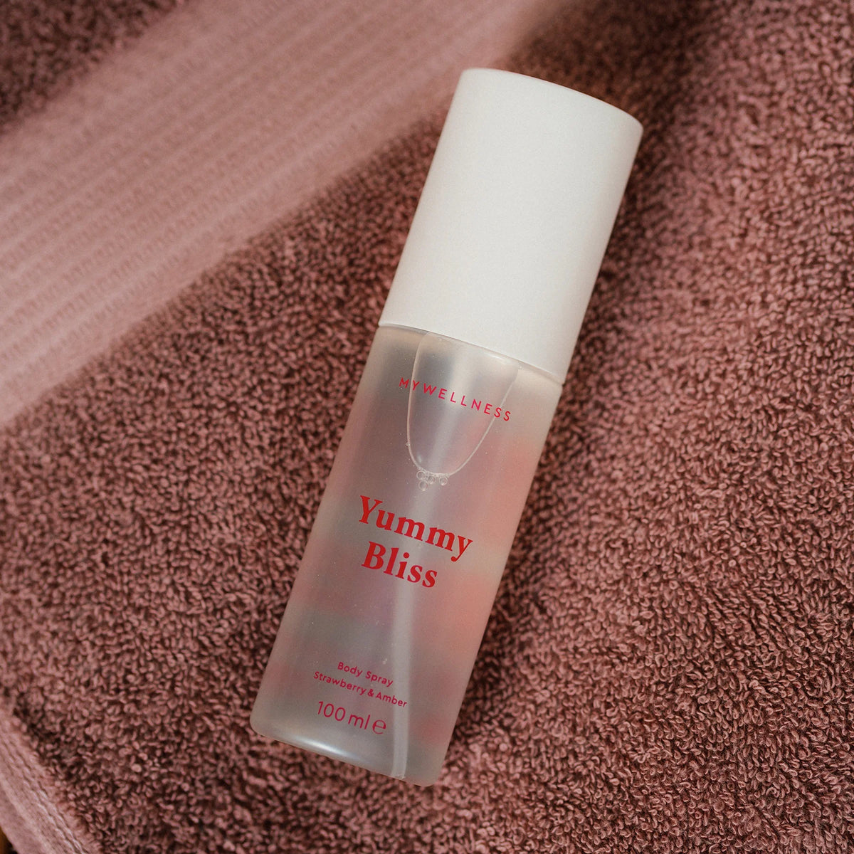 Yummy Bliss Body Spray mit Erdbeere und Amber von MyWellness liegt auf altrosa Frotteehandtuch