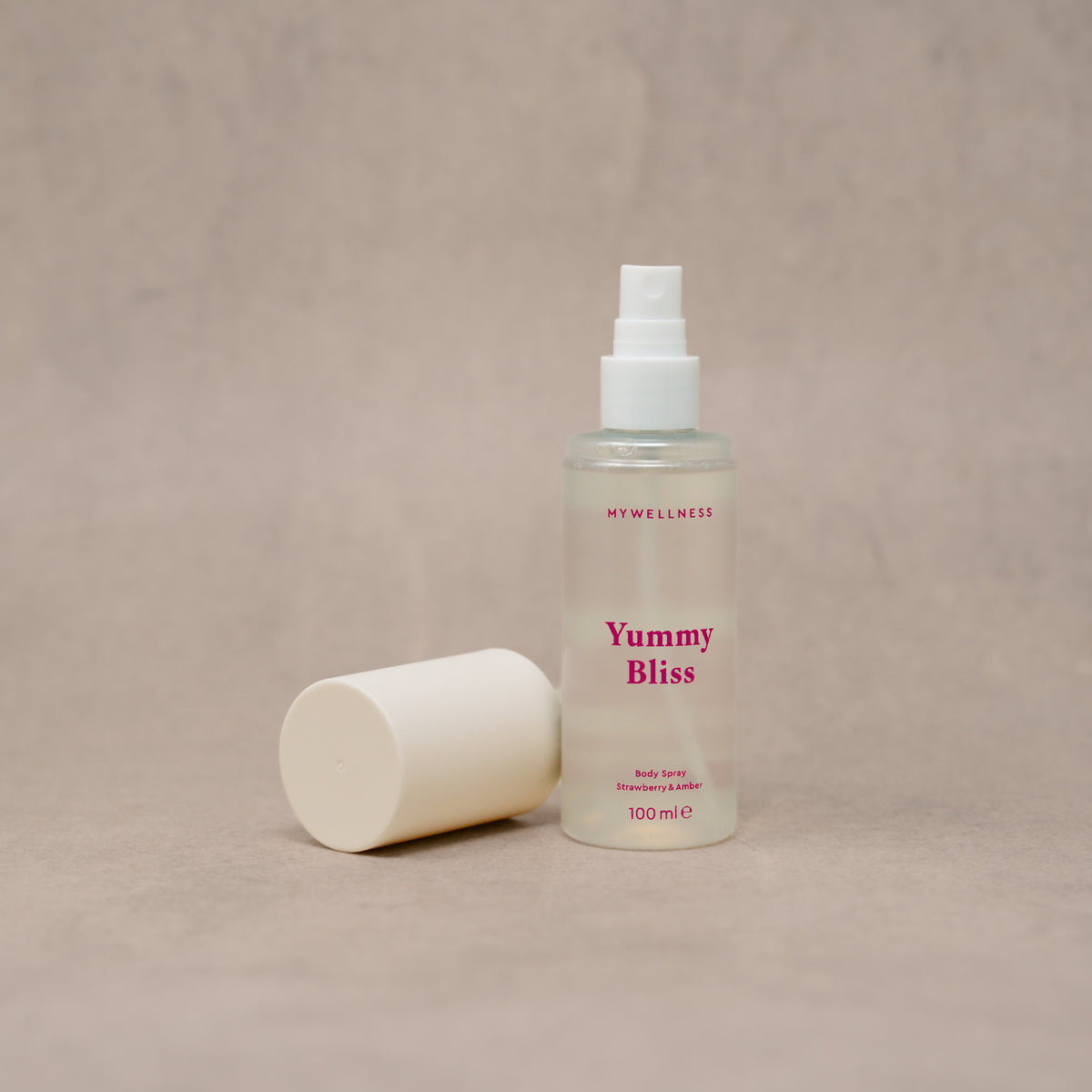 Yummy Bliss Body Spray von MyWellness mit abgenommener Kappe vor beigem Hintergrund