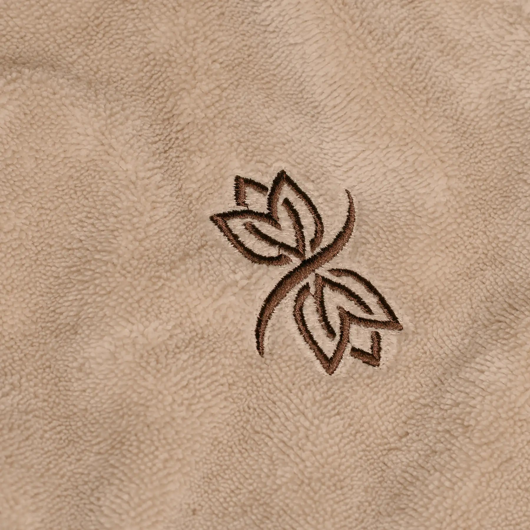 Lotus-Stickerei des MyWellness-Logos auf dem beigen MyWellness Bademantel – dezentes Wellness-Design mit feiner Stickerei