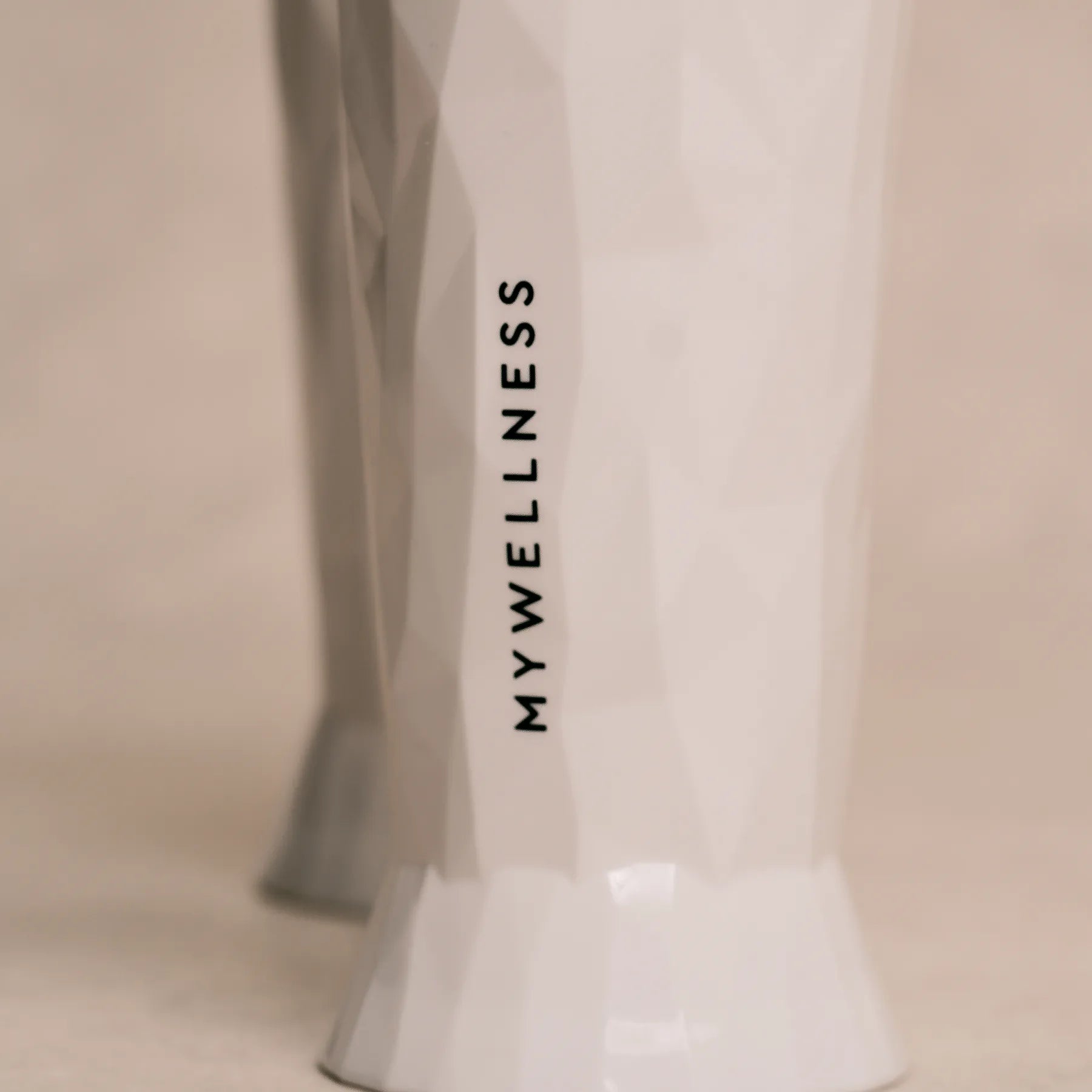 Strukturierte weiße MYWELLNESS-Biergläser mit vertikalem Logo, Nahaufnahme der eleganten Oberfläche.