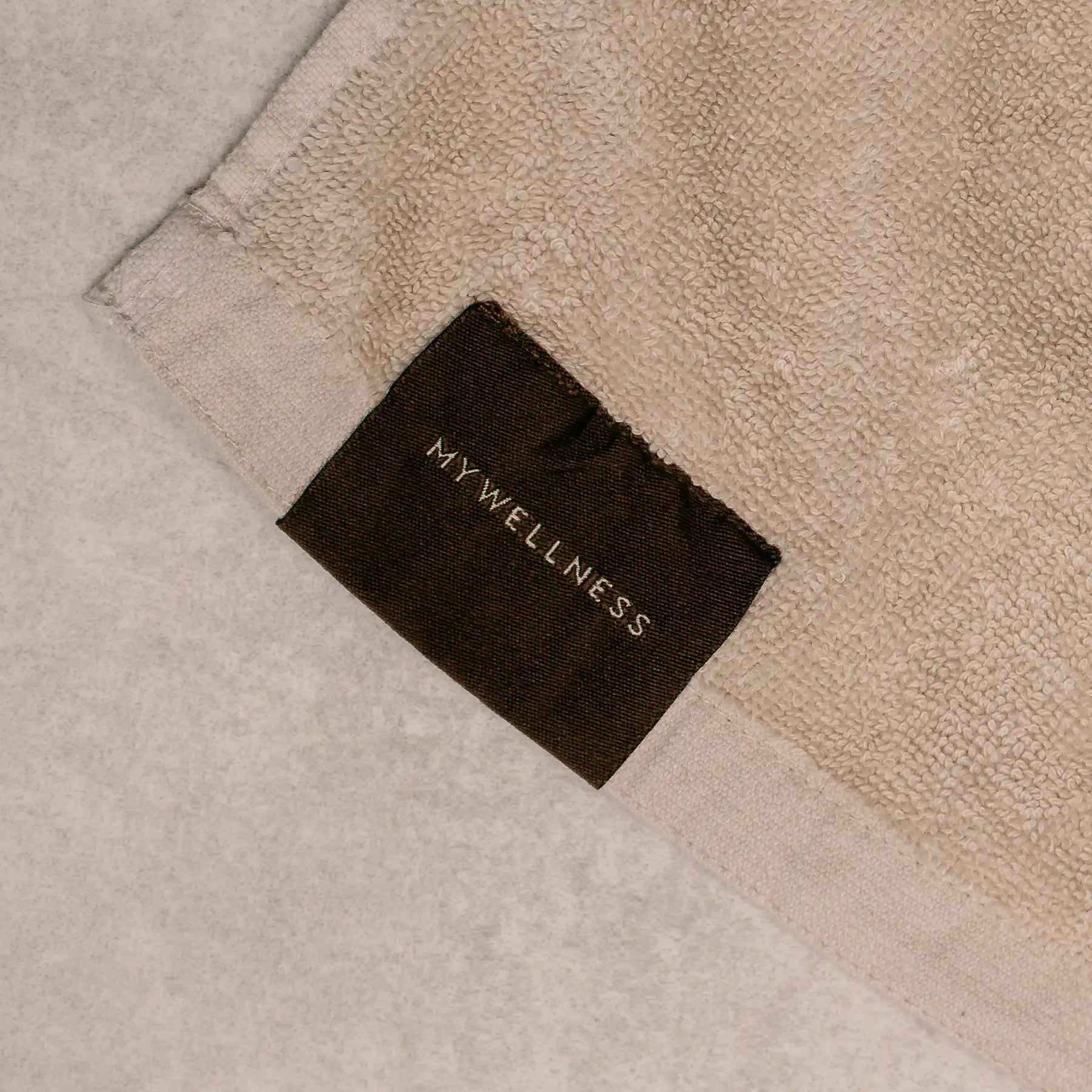 Gefaltetes MyWellness Saunatuch – luxuriöses Frotteetuch mit eingewebtem Muster und edlem Markenetikett
